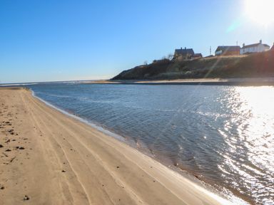 A sandy beach with water and houses on a hill in the background at Wansbeck View 2 in Ashington