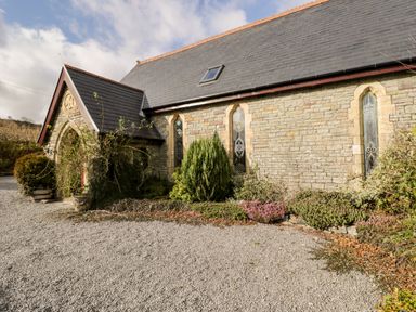 Exterior of a stone building with stained glass windows and gravel driveway at The Chapel in Dol-y-Gaer near Pontsticill