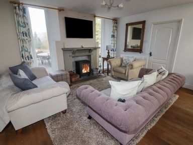 A living room with sofas a fireplace a wall-mounted TV and a wooden side table at The Chapel in Dol-y-Gaer near Pontsticill