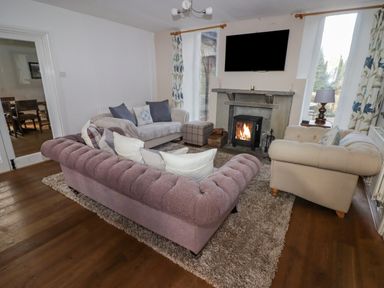 A living room with three sofas a fireplace and a wall-mounted television at The Chapel in Dol-y-Gaer near Pontsticill