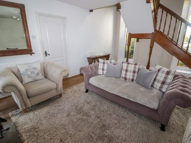 A sitting area with two sofas a large rug a mirror on the wall and wooden stairs at The Chapel in Dol-y-Gaer near Pontsticill