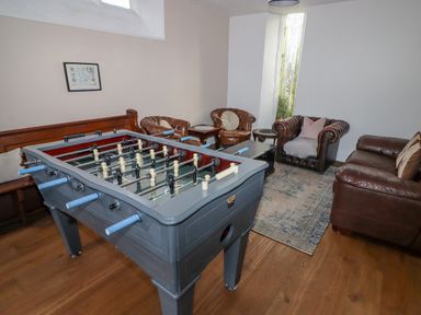 A game room with a foosball table and leather seating including armchairs and a sofa at The Chapel in Dol-y-Gaer near Pontsticill