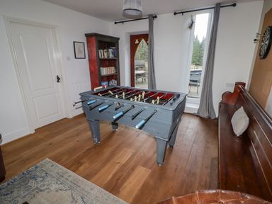 A room with a foosball table wooden bench bookshelf and dartboard at The Chapel in Dol-y-Gaer near Pontsticill