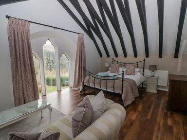 A bedroom with a bed sofa pillows and a window with curtains at The Chapel in Dol-y-Gaer near Pontsticill