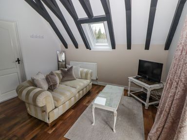 A small sitting room with a striped sofa a coffee table and a TV on a stand at The Chapel in Dol-y-Gaer near Pontsticill