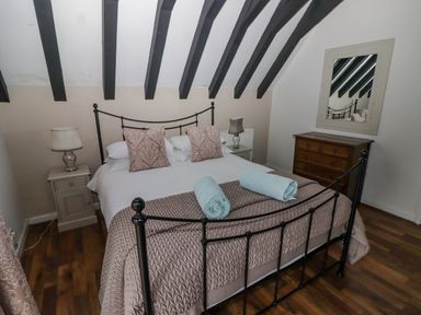 A bedroom with a double bed two bedside tables with lamps a wooden chest of drawers and a mirror at The Chapel in Dol-y-Gaer near Pontsticill