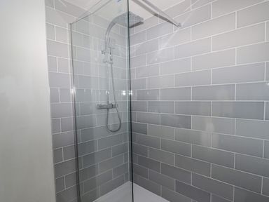 A shower area with a glass panel and gray subway tiles on the walls at The Chapel in Dol-y-Gaer near Pontsticill