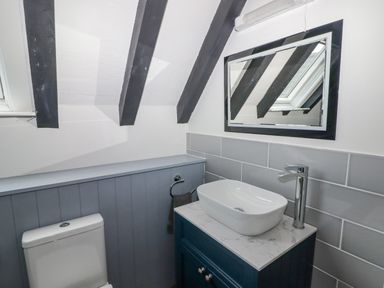 A bathroom with a toilet a sink on a countertop a mirror and exposed ceiling beams at The Chapel in Dol-y-Gaer near Pontsticill