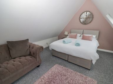A bedroom with a double bed two rolled towels a brown sofa and a pink rug at The Chapel Dol-y-Gaer near Pontsticill