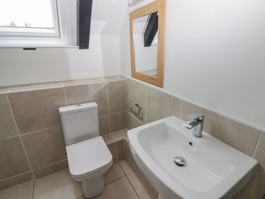 A bathroom with a toilet, sink, mirror, and window at The Chapel in Dol-y-Gaer near Pontsticill