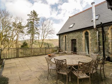 A stone patio with a round metal table and chairs outside a stone building at The Chapel Dol-y-Gaer near Pontsticill