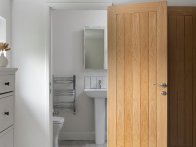 A bathroom with a toilet sink mirror and towel rack seen through a partially open wooden door at Sygun in Beddgelert