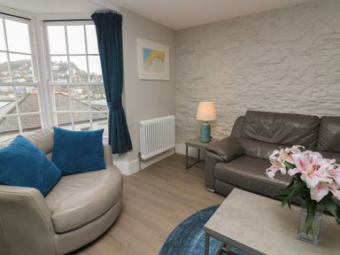 A living room with leather sofas blue cushions a lamp on a side table and flowers on a coffee table at Queens View in Dartmouth