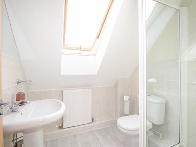 A bathroom with a pedestal sink a toilet a radiator and a skylight window at Anchors Away in Weymouth