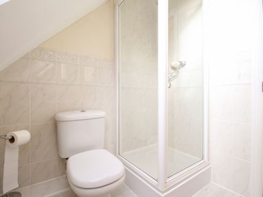 A bathroom with a toilet and a glass-enclosed shower at Anchors Away in Weymouth