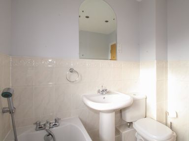 A bathroom with a white sink pedestal mirror toilet and bathtub at Anchors Away in Weymouth