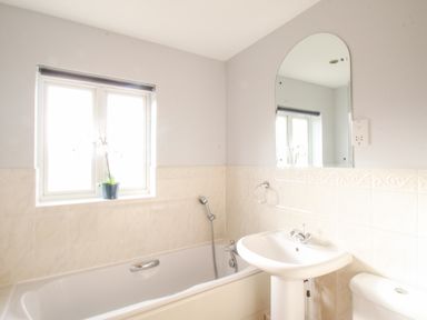 A bathroom with a bathtub a sink a toilet a window and a mirror at Anchors Away in Weymouth
