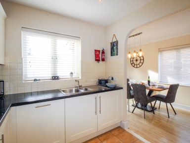 A kitchen with a countertop and sink next to a dining area with a table and chairs at Anchors Away in Weymouth