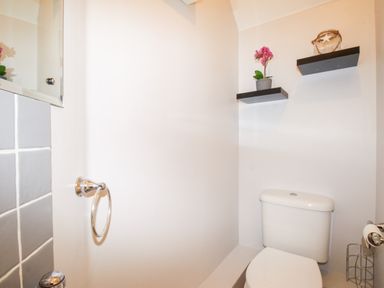 A bathroom with a toilet two floating shelves with decor and a towel ring at Anchors Away in Weymouth