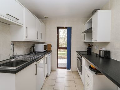 A kitchen with white cabinets black countertops a sink microwave kettle and toaster at The Lodge in Dol-y-Gaer near Pontsticill