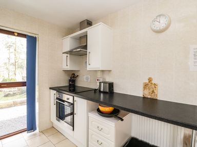 A kitchen with an oven stovetop toaster utensils cutting board and countertop at The Lodge in Dol-y-Gaer near Pontsticill