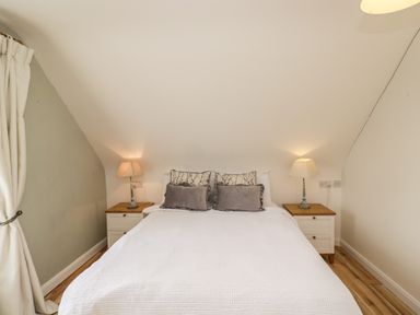 A bedroom with a double bed two bedside tables and two lamps at The Lodge in Dol-y-Gaer near Pontsticill