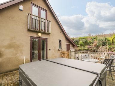 A patio with a covered hot tub table and chairs outside a house at The Lodge in Dol-y-Gaer near Pontsticill