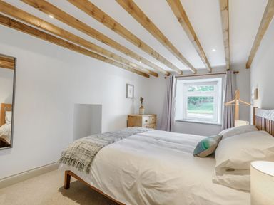A bedroom with a bed a dresser a mirror and a window at Morlan Cottage in Newport Pembrokeshire