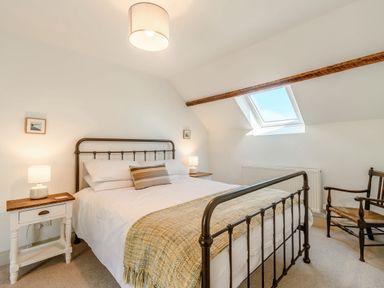 A bedroom with a metal bed frame a skylight wooden chair and bedside tables at Morlan Cottage in Newport Pembrokeshire