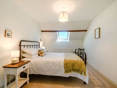 A bedroom with a metal bed frame bedside table with lamp and window at Morlan Cottage in Newport Pembrokeshire