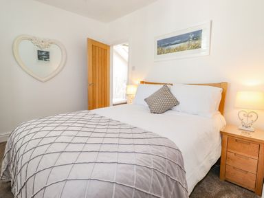 A bedroom with a bed side table and a heart shaped mirror at Chestnuts Cottage in Windermere