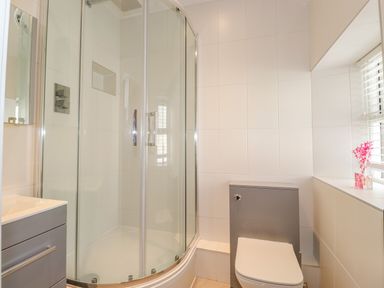 A bathroom with a corner shower enclosure a toilet and a sink with cabinet at Chestnuts Cottage in Windermere