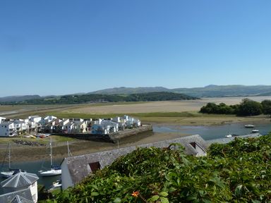 A coastal view with boats in water houses on a peninsula and hills in the background at Wenallt in Porthmadog