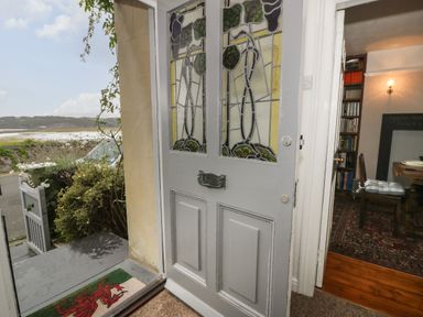 An open front door with stained glass panels looking out to a garden gate and landscape with hills at Wenallt in Porthmadog