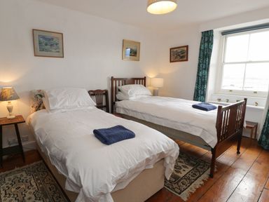 A bedroom with two single beds and framed pictures on the wall at Wenallt in Porthmadog
