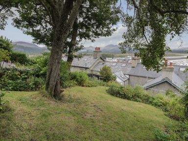 A garden with trees overlooking rooftops and mountains at Wenallt in Porthmadog