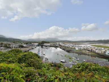 A harbor with boats docked and houses along the shoreline with mountains in the background at Wenallt in Porthmadog