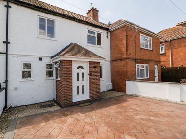 The front of a two-story house with a white door and brick porch at Seacider in Burnham-On-Sea