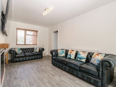 A living room with two black leather sofas and patterned cushions at Seacider in Burnham-On-Sea