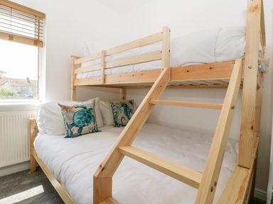 A bedroom with a wooden bunk bed and sea-themed pillows by a window at Seacider in Burnham-On-Sea