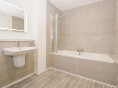 A bathroom with a wall-mounted sink and a bathtub with a shower screen at Seacider in Burnham-On-Sea