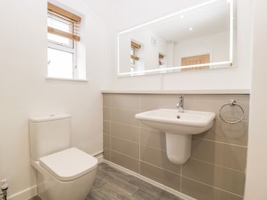 A bathroom with a toilet and a wall-mounted sink with a large mirror above at Seacider in Burnham-On-Sea