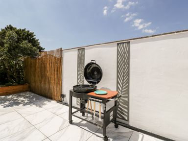 An outdoor patio with a barbecue grill a wooden privacy fence and plants at Seacider in Burnham-On-Sea