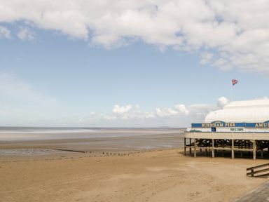A sandy beach with a pier building labeled Burnham Pier and a Union Jack flag at Seacider in Burnham-On-Sea