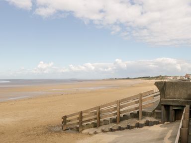 A sandy beach with wooden steps and a concrete structure near the shore at Seacider in Burnham-On-Sea
