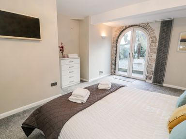 A bedroom with a bed and folded towels a chest of drawers and arched glass doors at The Chalet in Benllech
