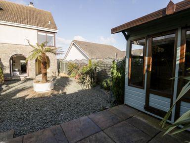 An outdoor courtyard with a tree in a planter and a garden shed at The Chalet in Benllech