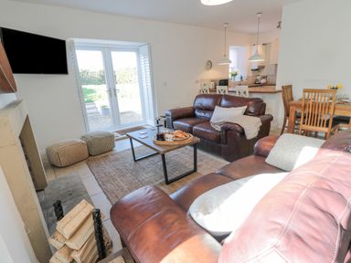 A living room with brown leather sofas coffee table and a dining table at Little Haven in Bamburgh