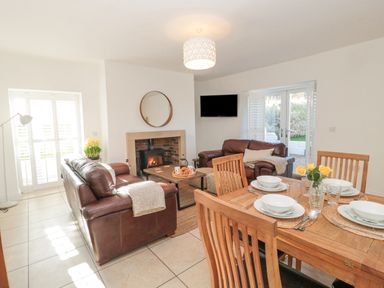 A living room with two brown leather sofas a wooden coffee table and a dining table set with plates and bowls at Little Haven in Bamburgh