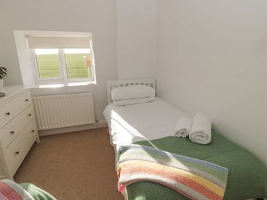 A bedroom with a single bed a chest of drawers and a window at Little Haven in Bamburgh